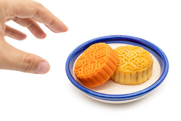 A hand taking moon cake on plate isolated on white background. Concept for Mid-Autumn Festival.
