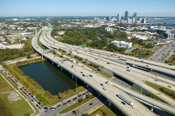 Fototapeta na wymiar Aerial view of Jacksonville city with high office buildings and american freeway intersection with fast driving cars and trucks. View from above of USA transportation infrastructure