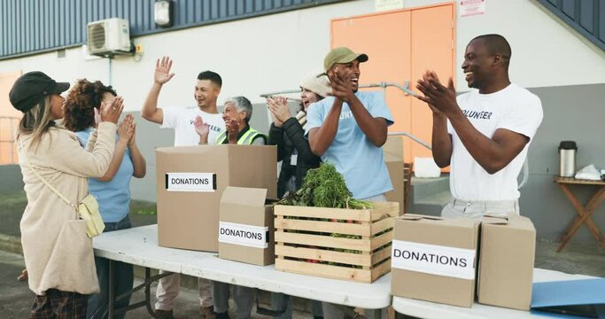 People volunteering, high five and donation success, teamwork and support, community service or NGO food boxes. Nonprofit group or men and woman applause, celebration and excited for charity project
