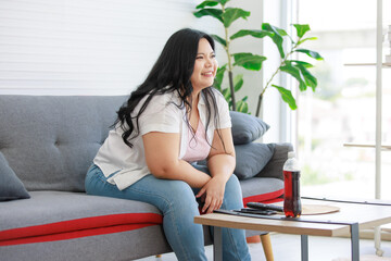 Asian young chubby fat unhealthy oversized lazy female teenager in casual outfit sitting on cozy...