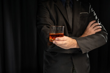 Close up shot of asian businessman holding glass of whiskey, alcohol, wine in hand with depression and sadness in face of financial or family problems.