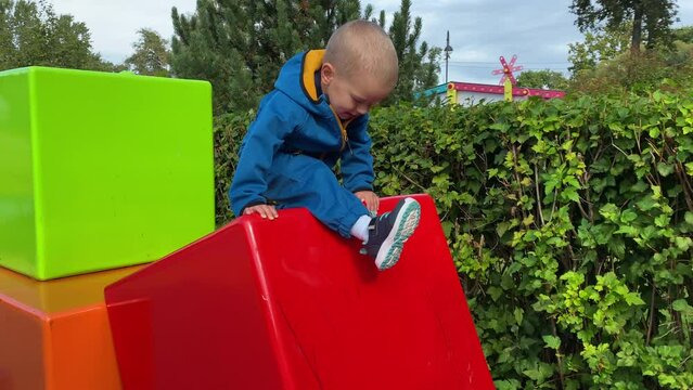 mother with toddler child in amusement park, happy little boy climbing on colorful cubes. Divo Island, St. Petersburg, Russia