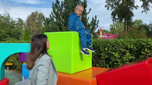 mother with toddler child in amusement park, happy little boy climbing on colorful cubes. Divo Island, St. Petersburg, Russia