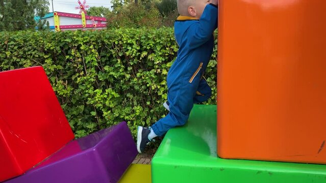 toddler child in amusement park, happy little boy climbing on colorful cubes. Divo Ostrov, St. Petersburg, Russia