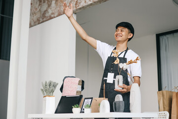 Happy seller asking the crowd to come looking at his craft products while smiling /