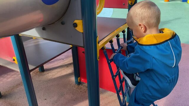 toddler child climbing an obstacle course on a playground, happy little boy in amusement park Divo Ostrov, St. Petersburg, Russia