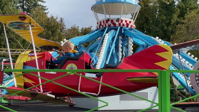 brave pilot toddler child in amusement park, attraction colorful airplanes will lift children Divo Ostrov, St. Petersburg, Russia