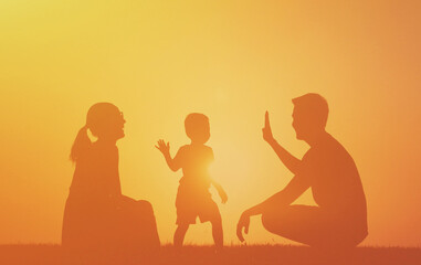 Happy family of three playing outdoors enjoying time together in the sunset. Good parenting loving family lifestyle concept. 