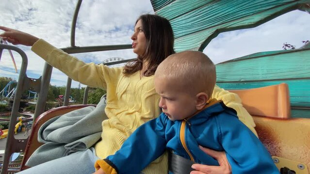 mother with child enjoy views of amusement park from height of 4 meters, traveling in a mobile, Divo Ostrov, St. Petersburg, Russia