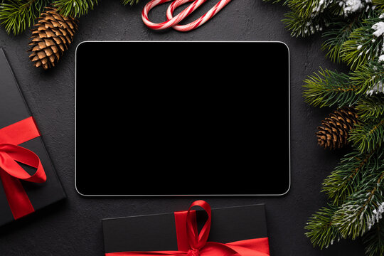 Tablet with blank screen, gift boxes and Christmas decor