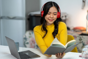 Cheerful Asian woman in headset laughing happily Listen to music, relax, use your laptop, stream video conference calls, teach online. hobby ideas work from home