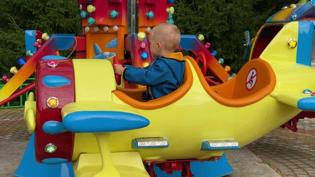 brave pilot toddler child in amusement park, attraction colorful airplanes will lift children Divo Ostrov, St. Petersburg, Russia