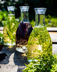 Vegetable oil in bottles on the table. Composition of bottles with rosemary and thyme oil. Fry the rosemary and thyme sprigs in olive oil. Bottles of oil on a wooden table. Selective focus.