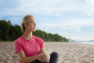 Fototapeta na wymiar Portrait of calm relaxed beautiful fitness girl sitting on the seashore