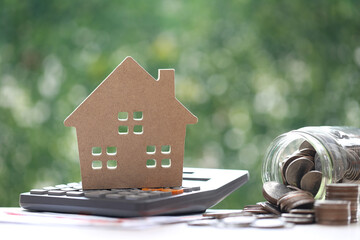 Finance, Model house on calculator and stack of coins money on natural green background,Business...