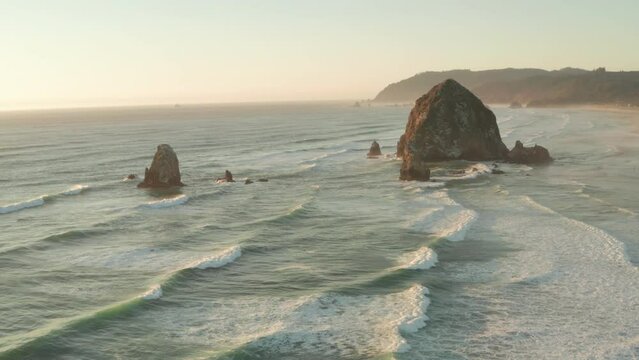 Wide circling aerial shot of Haystack rock at sunset