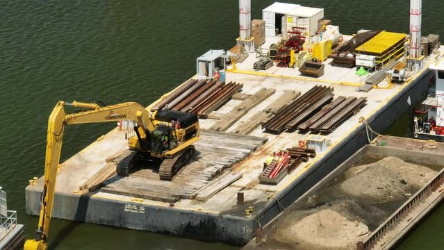 Excavator on a construction barge, carrying out the process of dredging.