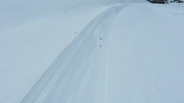High angle aerial tracking follows elite skier slalom racing across fresh groomed run