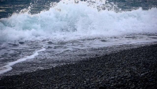 Ocean Waves Over a Shingled Beach of Pebbles with a Low Angle Perspective in Slow Motion.