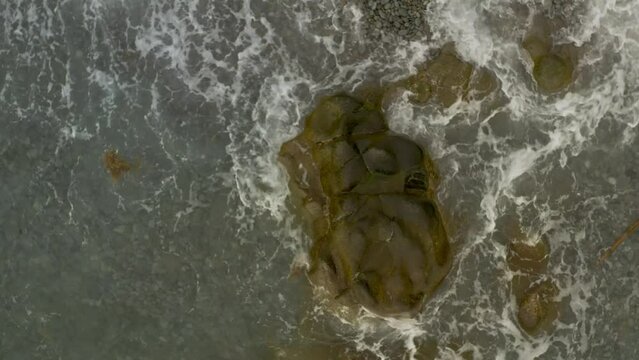 Top Down View Over a Boulder of Rocks on a Beach with Ocean Waves in Looc Bay, Philippines.