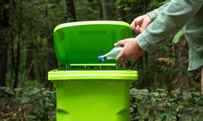  Man throwing plastic bottle into trash bin.