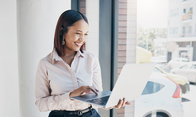 Woman in office with smile, holding laptop and reading email, HR schedule or online for feedback at window. Internet, networking and communication on website, happy person and human resources agency