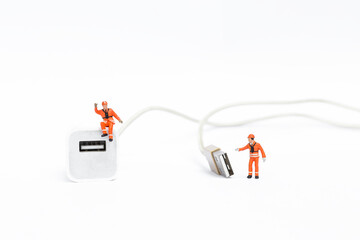 Miniature worker in safety suit with USB charging cable, standard charging port for electronic devices 