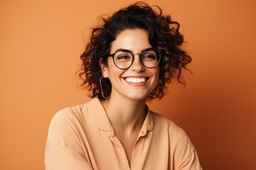 Portrait of a smiling young woman in eyeglasses on orange background - obrazy, fototapety, plakaty