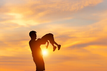 Silhouettes of father and son playing outdoor blurred sunset evening sky background, Father's day concepts