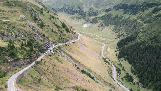 Sheer drop off next to pull offs showcase large u bend in Transfagarasan Serpentine Road cutting through romanian forests