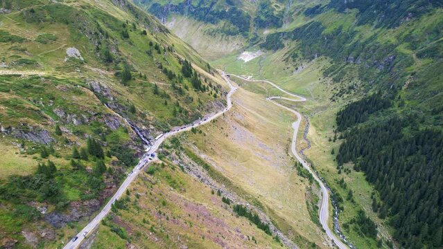 Slow push in aerial dolly of Transfagarasan Serpentine Road waterfall and valley hairpin turn
