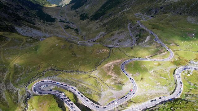 Top down bird's eye view of treacherous Transfagarasan Serpentine Road switchbacks covered in shadow of mountain ridges