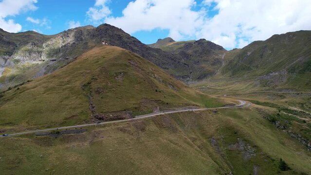 Aerial descend below Transfagarasan Serpentine Road lush green mountains at midday