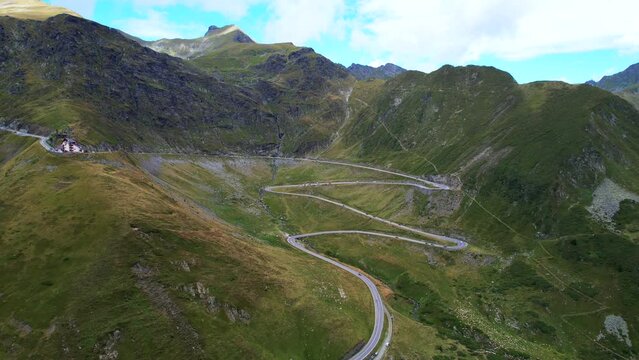 Right to left trucking pan above Transfagarasan Serpentine Road romania, midday green mountainside