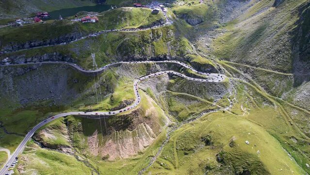 cinematic aerial dolly tilt up above Transfagarasan Serpentine Road and electricity pylons, traffic stopped at pull offs