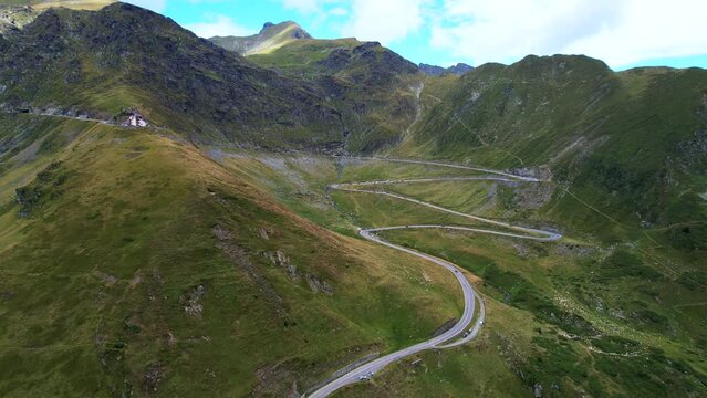 View of switchbacks and scenic overlook pull off on Transfagarasan Serpentine Road as cars drive at midday