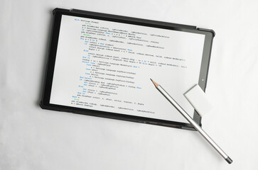 Programming and coding concept. Writing utensils - a pencil and an eraser lie on top of the screen with a program listing