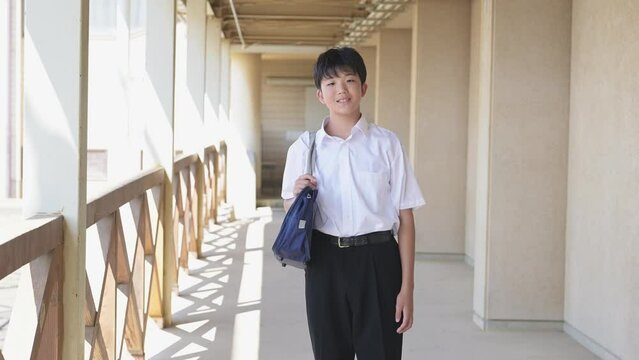 学校の校舎と学生服を着た男子学生