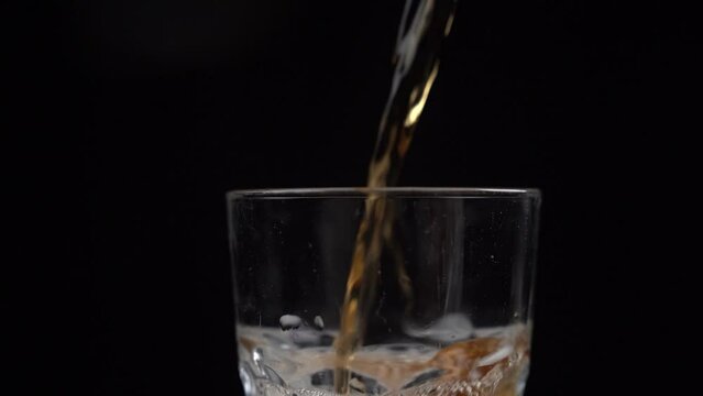 Pouring Carbonated Iced Tea Into A Glass With Black Background 