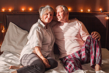 Happy elderly couple wakes up in bed in the morning