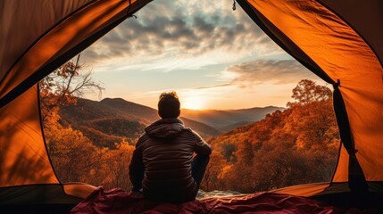 Traveler holding relaxing inside a orange tent and enjoy the view of sunset on autumn forest in national park Generative ai