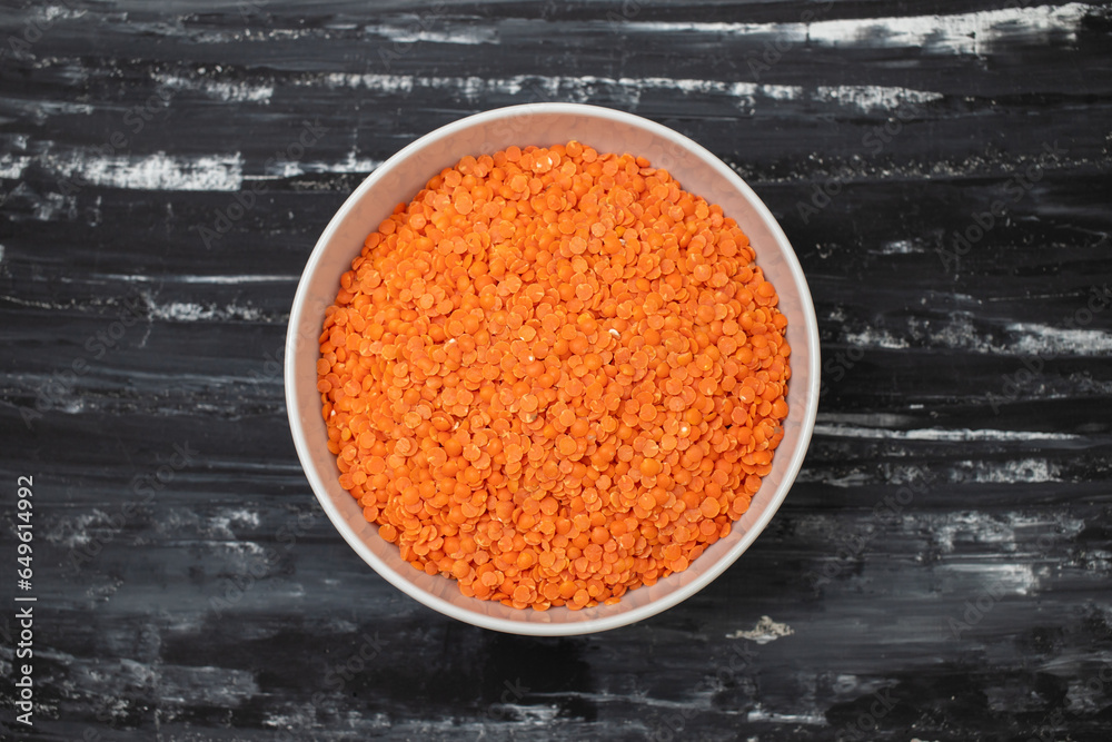 Poster uncooked red lentils in white bowl on ceramic