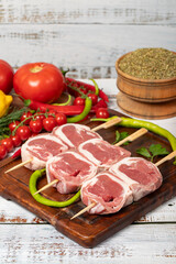 Lamb tenderloin skewer on wood background. Raw lamb tenderloin beyti skewer with herbs and spices