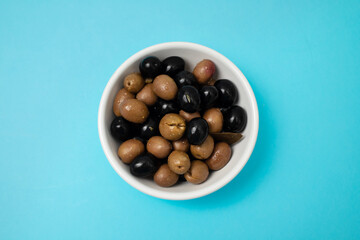 green and black salted olives in white bowl