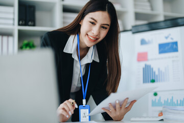 Beautiful young teen asian businesswoman using laptop computer and paperworks with planning working on financial document, tax, exchange, accounting and Financial advisor