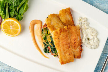 Fried Panga Fillet with greens and onions on the side and spinach underneath