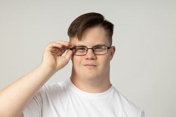 A smiling young man with cerebral palsy in glasses and a white T-shirt poses for the camera. World...
