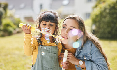 Mother and girl child blowing bubbles together on grass in nature for picnic, happiness and love....