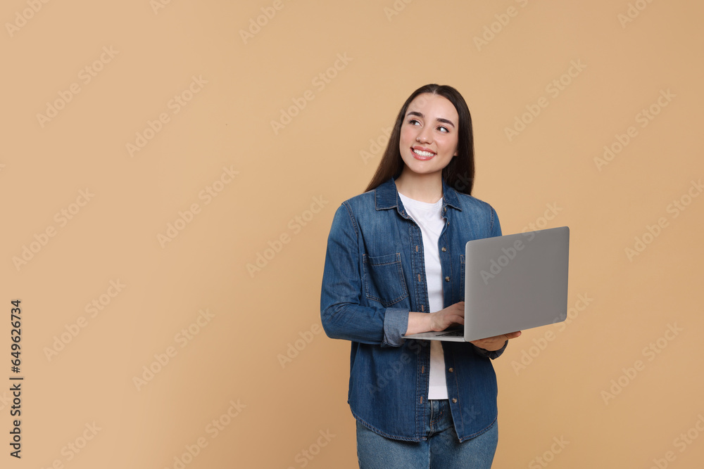 Poster Smiling young woman with laptop on beige background, space for text