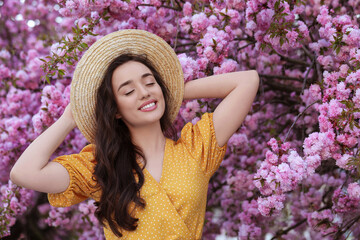 Beautiful woman near blossoming sakura tree on spring day